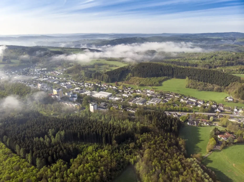 Wide aerial drone view showing town, landscape, and terrain used as real-world context for 3D rendering